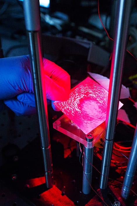 A fushia laser is shot on a glass slide with blood that is coated with magnetic beads to reveal protein concentration.