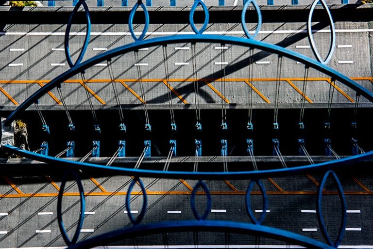 A top-down view of a two-way bridge with blue arches and a series of evenly-placed cables