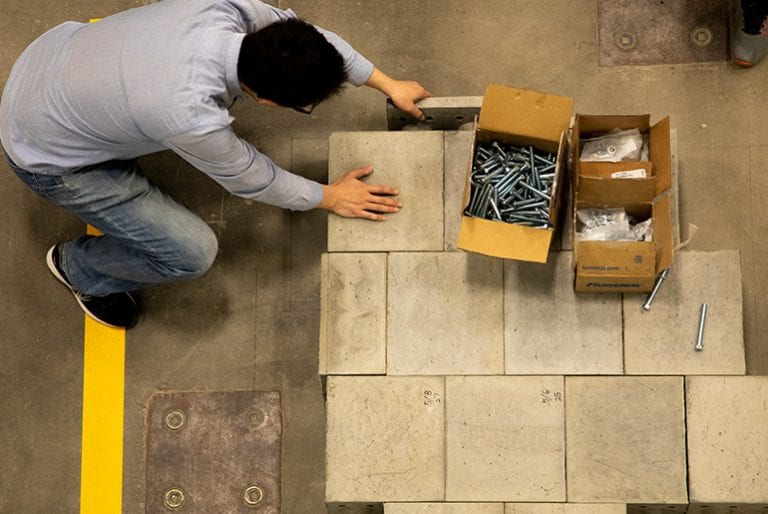 An aerial view of a student aligning concrete blocks in an organized pattern on the floor