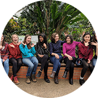 Members of the all-female student org ECSEL laugh and pose with silly faces in a botanical garden