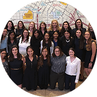 A large group of members of “Society of Women Engineers” pose for a picture in front of a wall-sized map of Minneapolis.