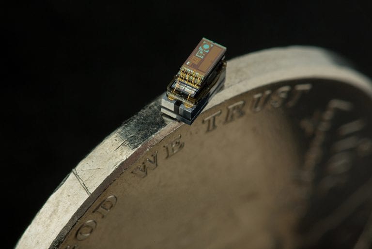A fully functional microcomputer made by EE faculty and students made up of sheets of metal and wires sits at a coin's edge