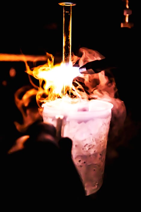 White hot flames and steam mix and flow over the edges as a blowtorch is taken to a beaker