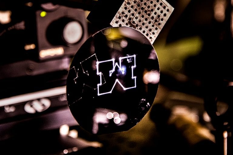 A Block-M is cut onto a wafer by a laser in the optics lab and glows white