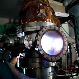 An experiment for developing better interplanetary transport glows blue and purple in a metal thruster discharge chamber